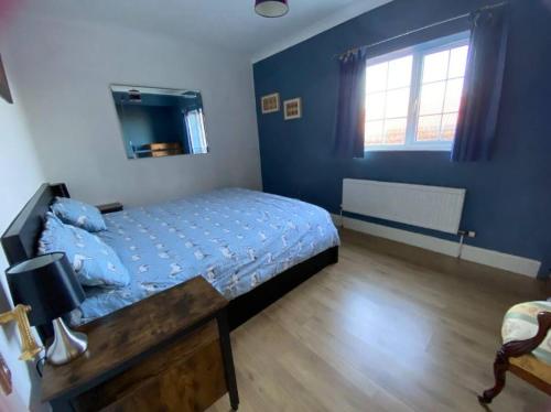 a bedroom with a bed and a blue wall at Wellbet Farm in Swinderby