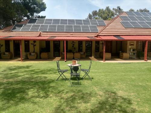 a person sitting at a table in front of a house with solar panels at A Cherry Lane Self Catering and B&B in Bloemfontein