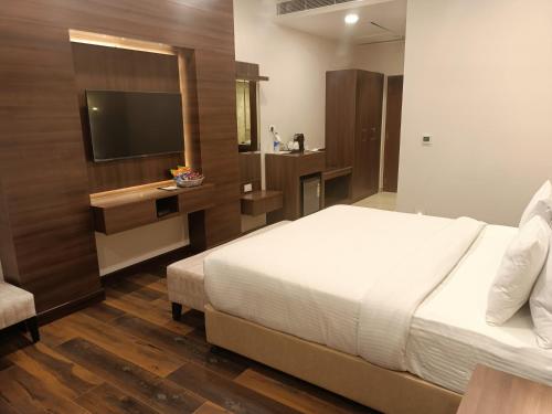 une chambre d'hôtel avec un lit et une télévision dans l'établissement M B Greens Clarks Inn, à Moradabad