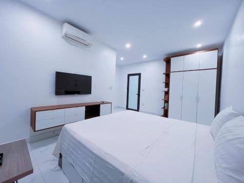 ein weißes Schlafzimmer mit einem Bett und einem TV in der Unterkunft Homestay Sunny in Thái Nguyên