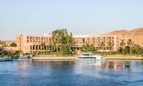 Pyramisa Island Hotel Aswan في أسوان: قارب في الماء امام مبنى كبير