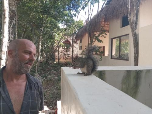 a man standing next to a squirrel on a wall at Villa AHAL, in Chemuyil
