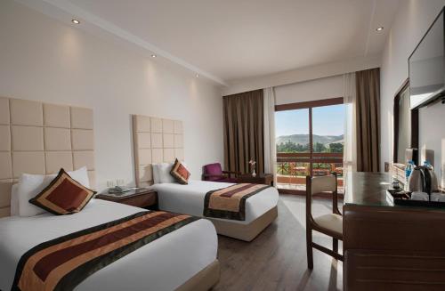 a hotel room with two beds and a balcony at Pyramisa Island Hotel Aswan in Aswan
