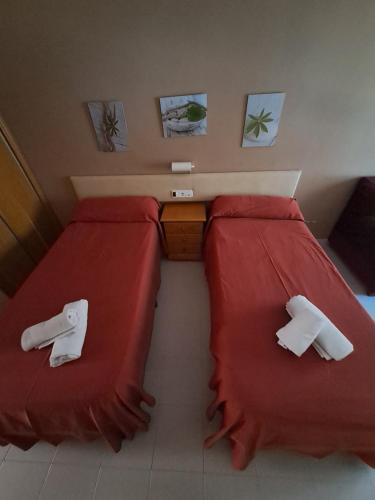 a bedroom with two beds with red sheets at EL MESON in Mequinenza