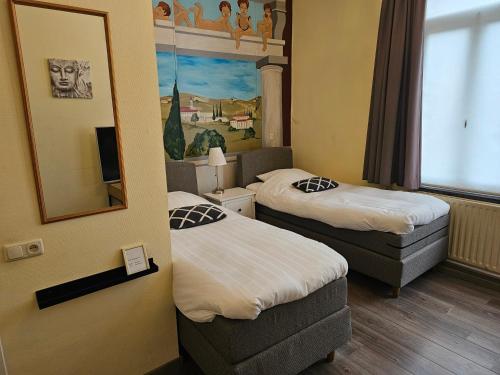 a hotel room with two beds and a mirror at hotel le bonheur in Eijsden