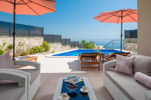 a patio with chairs and umbrellas next to a pool at Villa Harmony in Makarska
