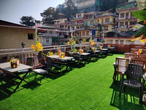 a group of tables and chairs on a lawn with buildings at Hotel Akash - Luxury Hotel In McLeodganj in McLeod Ganj
