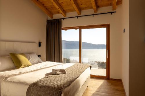 a bedroom with a bed and a large window at Colago Private Villas Lake Garda in Toscolano Maderno
