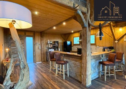 - une cuisine en rondins avec un bar et des tabourets dans l'établissement Luxueux chalet 5 chambres, à Brizon
