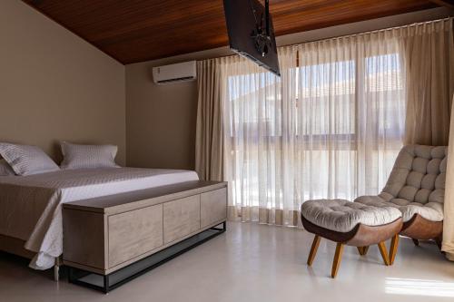 a bedroom with a bed and a chair and a window at Casa Brisa da Villa - Outeiro das Brisas - Espelho in Praia do Espelho