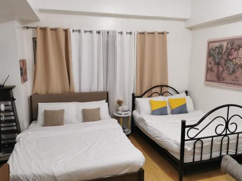 twee bedden in een kamer met witte muren bij Unit 402, Cedar Peak in Baguio