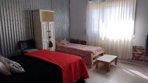 1 dormitorio con 2 camas y manta roja en la casa de gales habitación privada con baño en Puerto Madryn