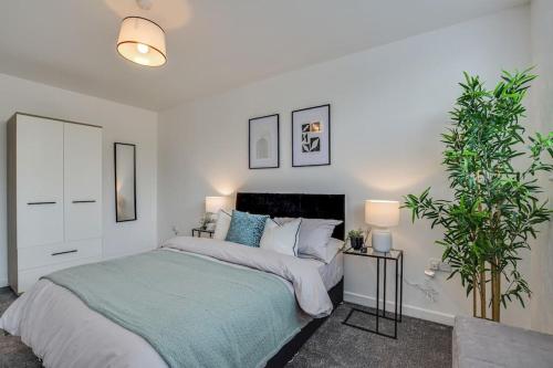 a bedroom with a bed and two potted plants at Luxury 2-Bedroom Formby Property in Formby