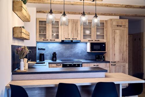 una cocina con armarios de madera y una mesa con sillas. en Resort Bobrovník, en Lipová-lázně