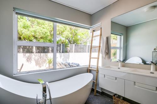 a bathroom with a tub and a sink and a window at Houghton Views in Cape Town