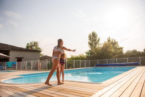 Deux filles se tiennent à côté d'une piscine dans l'établissement Camping Fargogne, à Puygaillard-de-Quercy