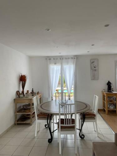 une salle à manger blanche avec une table et des chaises dans l'établissement Charmante Maison entre châteaux et océan, à Cussac-Fort-Medoc