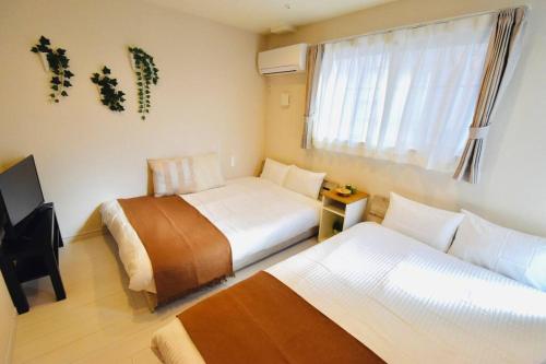 una camera d'albergo con due letti e una televisione di NEW!! 浅草 スカイツリー近く 貸切最大5人 東京観光に最適 無料WiFi a Tokyo