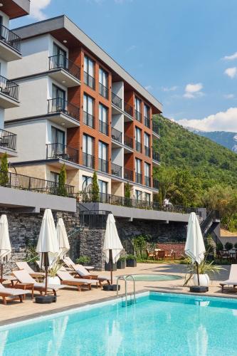 a hotel with a swimming pool with chairs and umbrellas at Bayview Hills Luxury Residences in Tivat