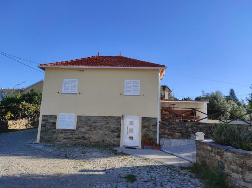 a small white house with a stone wall at Moradia Largo do Pátio in Sertã