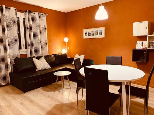 a living room with a black couch and a table at Chalet Le Nordique Bain Nordique Sauna in Fréchet-Aure