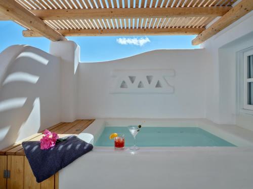 a hot tub in a white room with a wooden ceiling at Zefi Hotel & Suites in Naousa