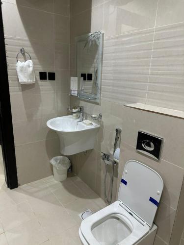 a bathroom with a white toilet and a sink at أجنحة رونق العلا 2 in Al-ʿUla