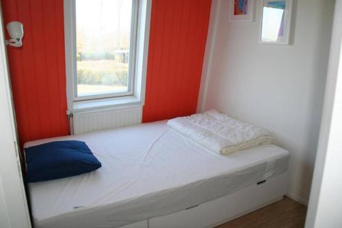a small bed in a room with a window at Lamsoor 9C in Nieuwvliet