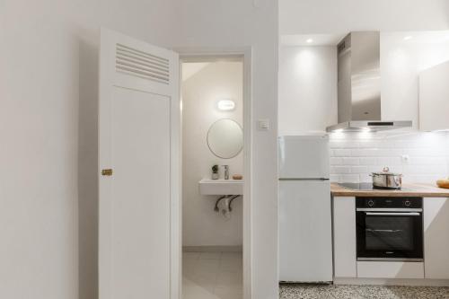 a white kitchen with a refrigerator and a sink at Esperos Apartment in Skopelos Town