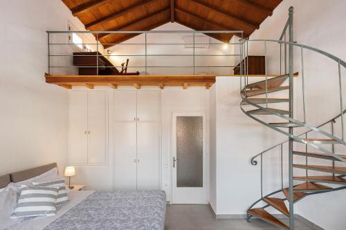 a spiral staircase in a room with a bed at Esperos Apartment in Skopelos Town