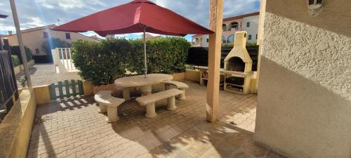 un patio avec une table, un parasol et un barbecue dans l'établissement 3 Pièces Rés Patios Du Barcares village 61m2 et climatisé, au Barcarès
