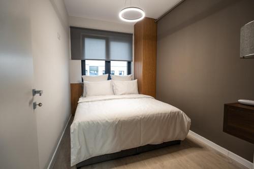 - une chambre avec un lit doté de draps blancs et une fenêtre dans l'établissement Blvd Ivory Pipera ap.70A, à Bucarest