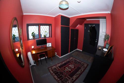 スタヴァンゲルにあるCharming apartment in central Stavangerの赤い壁の客室で、デスク(パソコン付)が備わります。