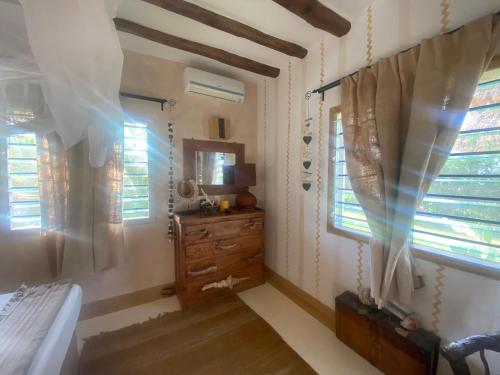 a bedroom with a bed and a dresser and windows at White bay pianoB in Watamu