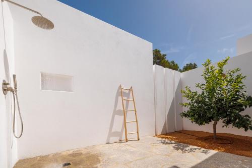 a ladder leaning against a white wall next to a tree at Can Lluc Suites & Villas Ibiza's Peaceful Getaway in Sant Rafael de Sa Creu