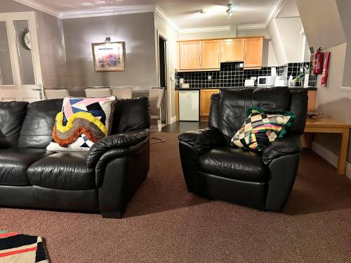 a living room with two leather chairs and a kitchen at Spacious 2 bedroom apartment in Killarney in Killarney