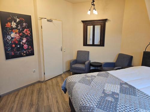 a bedroom with two chairs and a bed and a painting at hotel le bonheur in Eijsden