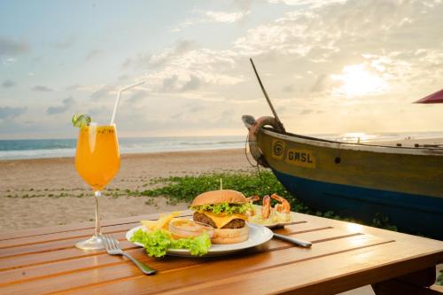 a table with a sandwich and a drink and a boat at Villa Jungle & Wiener in Habaraduwa