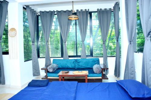 a living room with a blue couch and a large window at YT Inn Arambol in Old Goa
