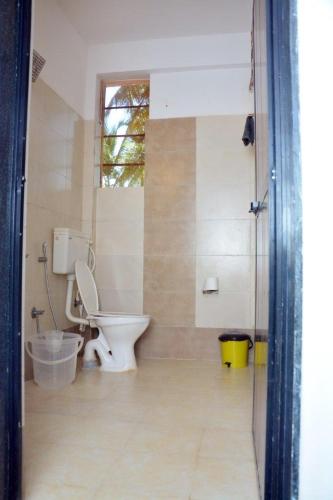 a bathroom with a toilet and a window at YT Inn Arambol in Old Goa