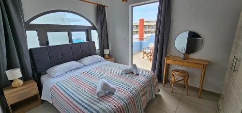 a bedroom with a bed and a mirror and a balcony at North Bay Apartments in Rhodes Town