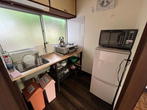 a small kitchen with a microwave and a refrigerator at 下呂スプリングスロッジ in Gero