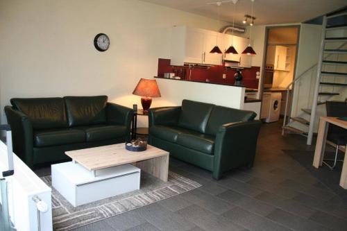 a living room with two green couches and a table at Heggerank 32 in Nieuwvliet