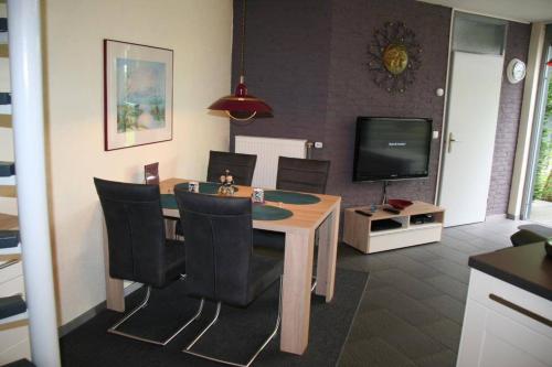 a dining room with a table and chairs and a television at Heggerank 32 in Nieuwvliet