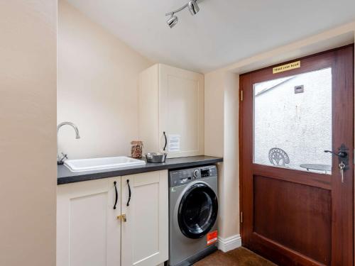 a kitchen with a washing machine and a window at 2 bed in Tywyn 83956 in Abergynolwyn