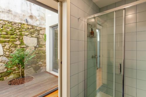 a glass shower in a bathroom with a stone wall at Yellow Lodge - Minho's Guest in Braga