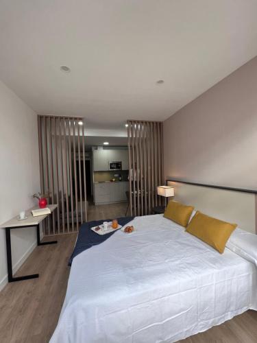um quarto com uma grande cama branca e uma cozinha em Apartamentos San Juan Suites em Badajoz