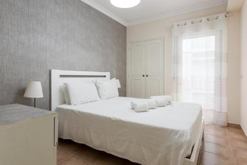 - une chambre avec un lit blanc et des serviettes dans l'établissement Jaune - 50 meters to the beach - Quarteira, à Quarteira