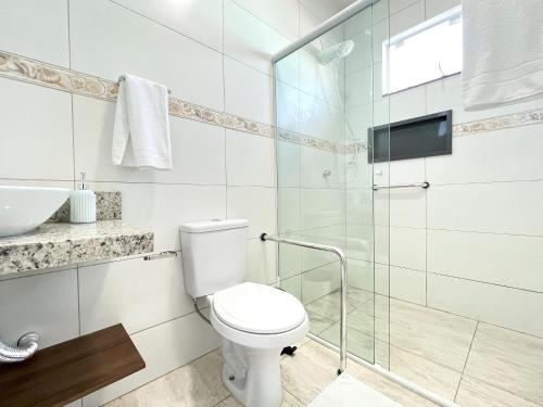 a bathroom with a toilet and a glass shower at Morada das Marés - Balneário Barra do Sul in Balneario Barra do Sul