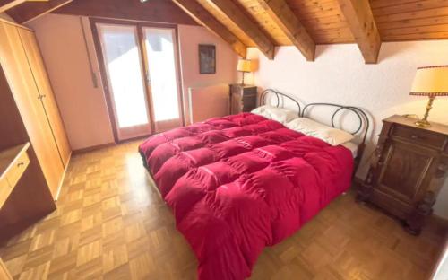 a large red bed in a room with a window at tHE Eagle Nest Duplex - Your Mountain Retreat in Chalais